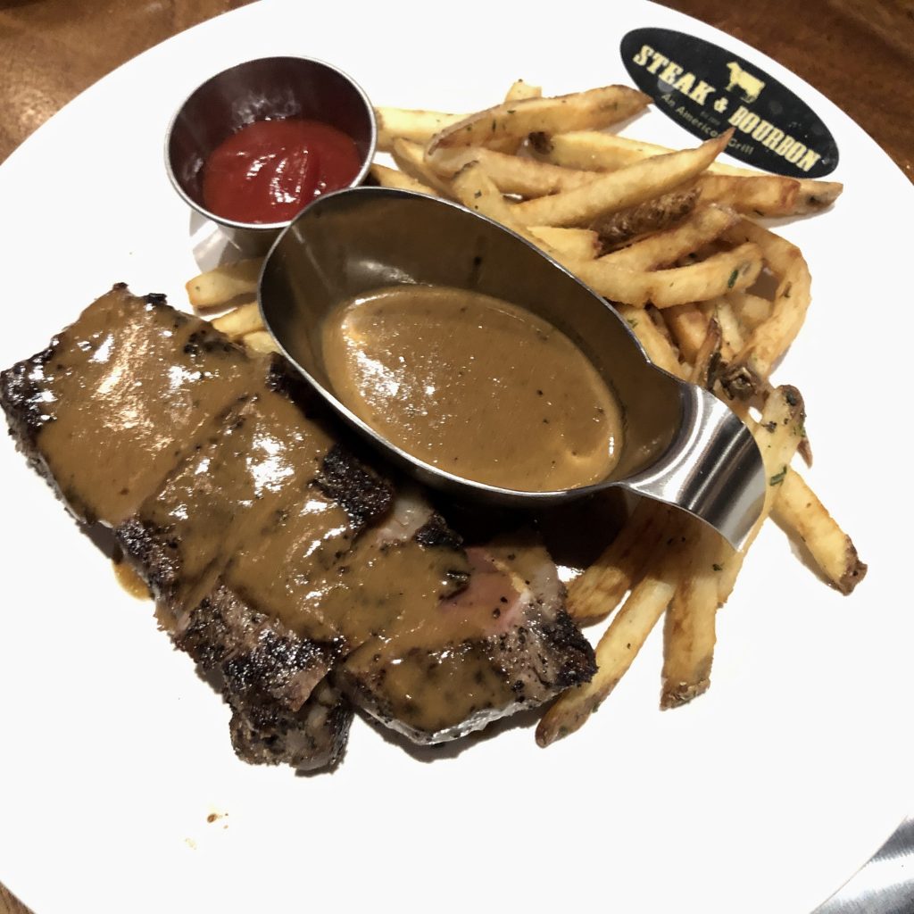 Steak & Bourbon’s steak and frites features New York strip steak au poivre.