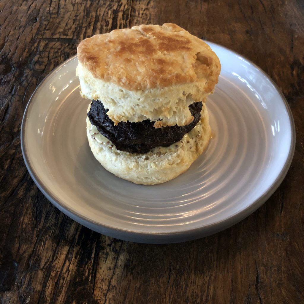 A lofty biscuit the size of a hockey puck makes a sandwich with hot-and-spicy sausage at Butchertown Grocery Bakery.