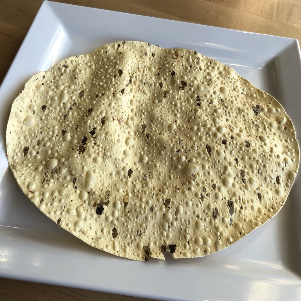 Honest's lentil-flour papads are crisp and shattery, dotted with tiny bubbles and bits of spice.