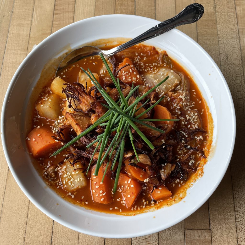 Jjigae is a hearty, spicy Korean dish of hot-sour broth filled with carrots, potatoes, and fiery kimchi. Monnik makes it a veggie dish with jackfruit filling in for meat.